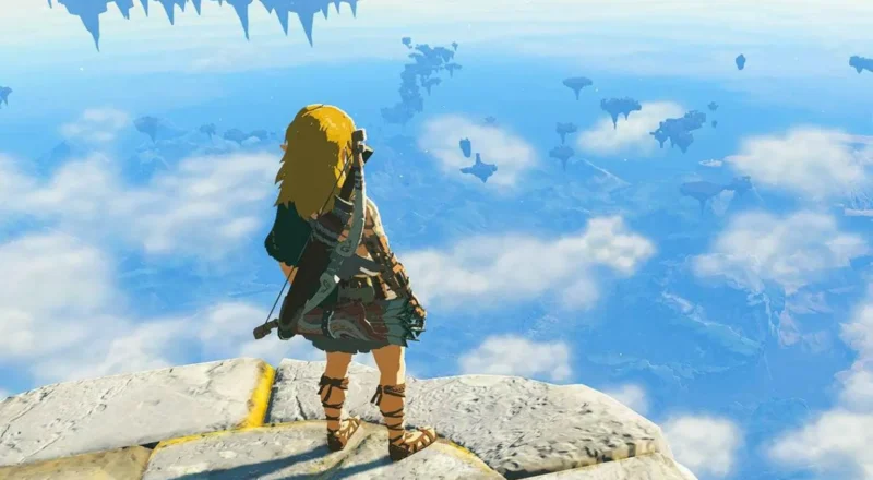Nintendo A screenshot from a video game showing a character, with long blond hair, a tunic and carrying a bow and arrows on his back, standing on the edge of a stone platform looking over a fantasy skyscape.