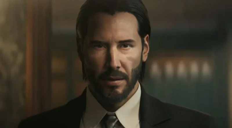 Lionsgate and Saber Interactive An in-game screenshot of a video game version of Keanu Reeves as the character John Wick. He is wearing a suit and looking at the camera.
