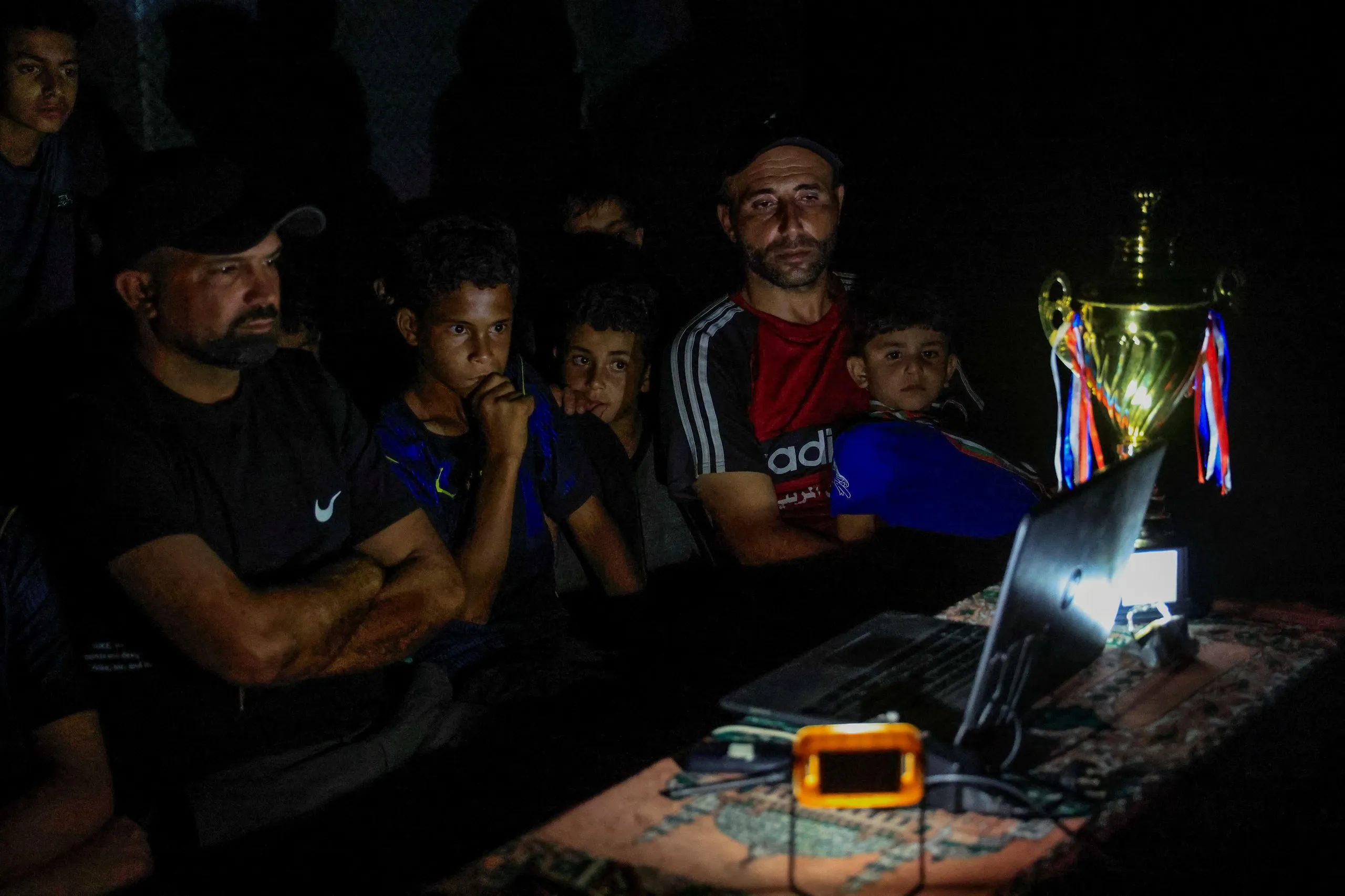 In the southern Gaza Strip, former Palestinian football player Fadi Al-Arawi watches a 2026 World Cup match streamed on a laptop alongside others in Khan Younis.