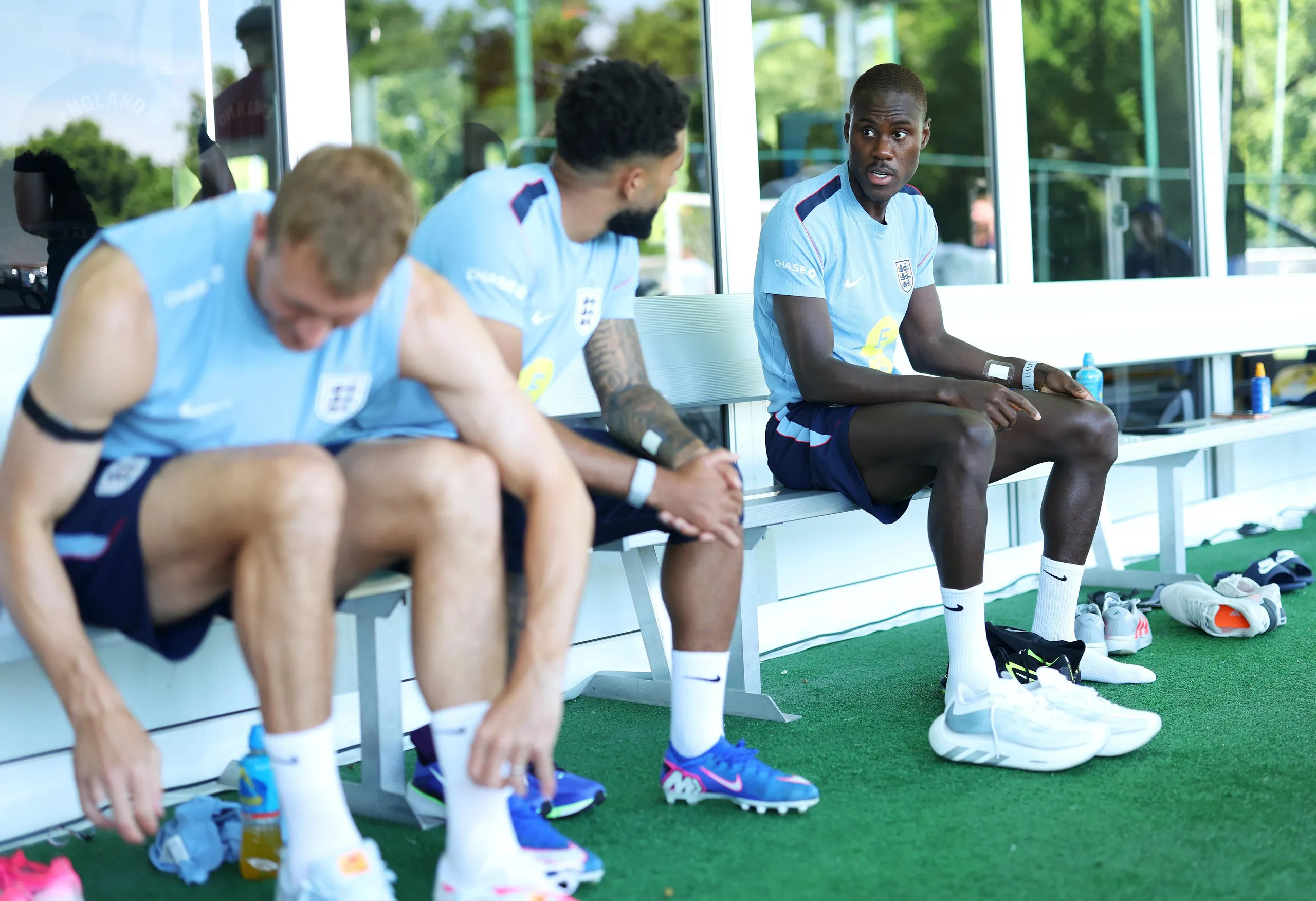 Trevoh Chalobah sitting on a bench at England’s training camp talking to Reece James
