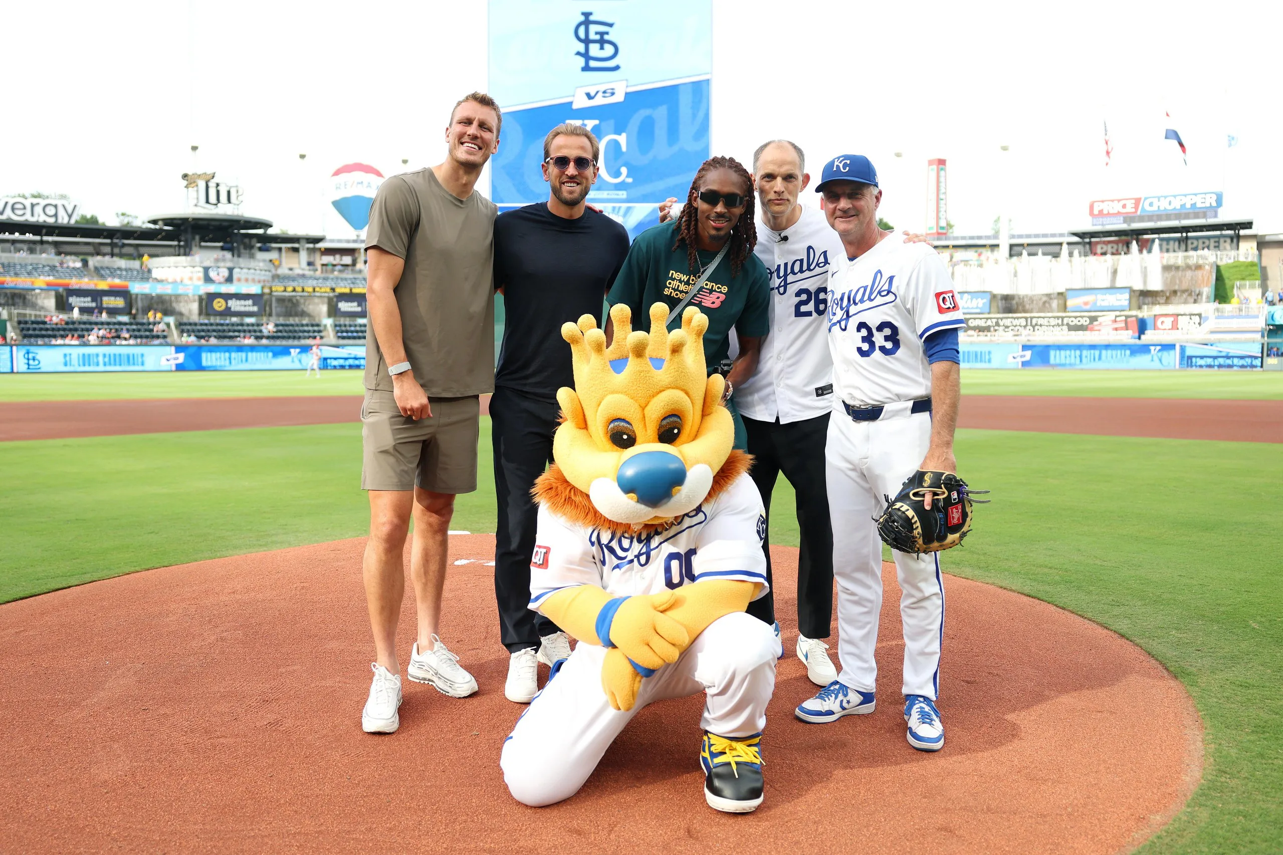 Dan Burn, Harry Kane, Djed Spence and Thomas Tuchel pose for a photograph alongside mascot Sluggerrr and Matt Quatraro, manager of the Kansas City Royals