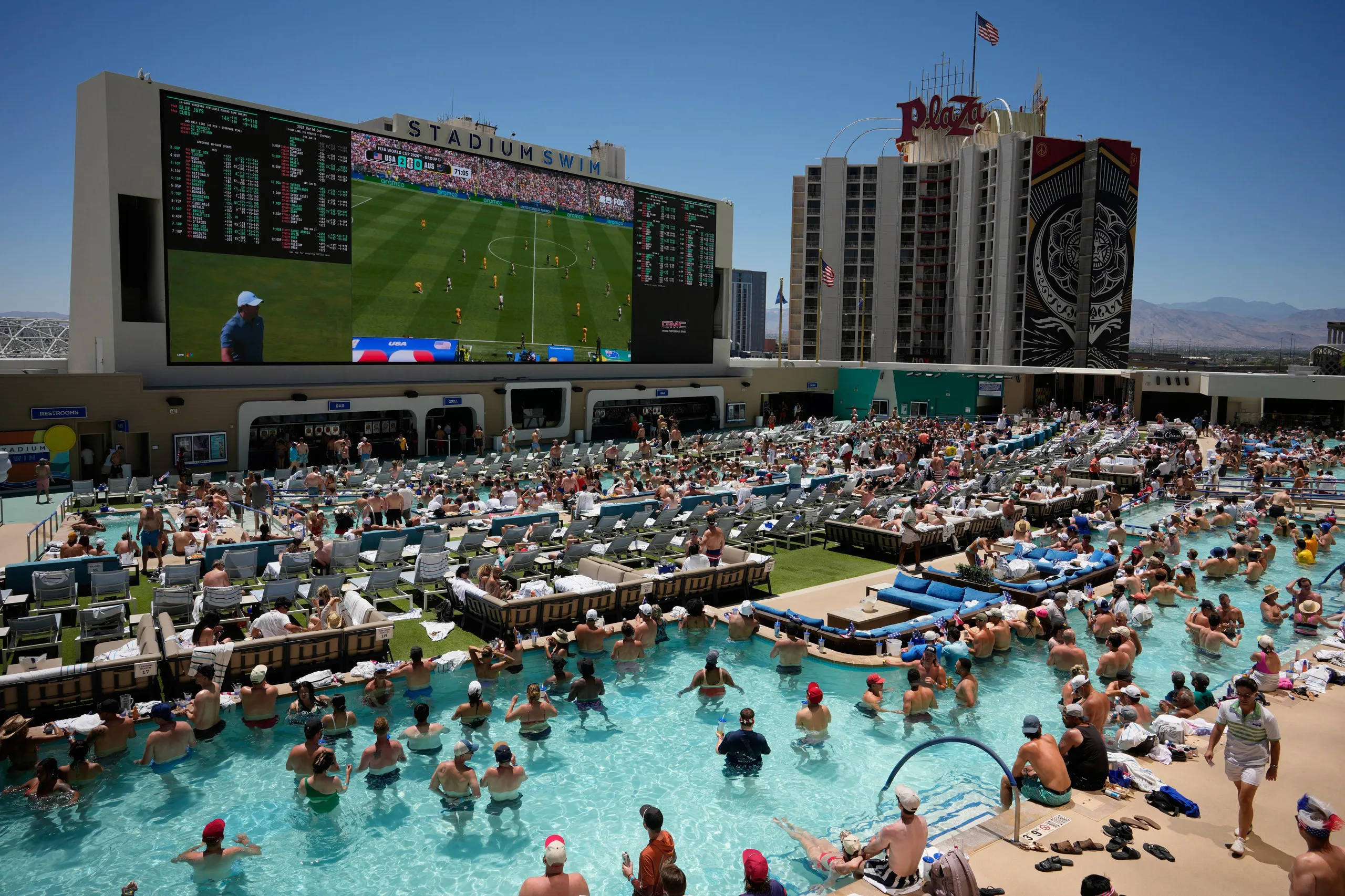 Swimmers in pool at the Circa Resort & Casino in Las Vegas watching a live broadcast of a World Cup match between USA and Australia.