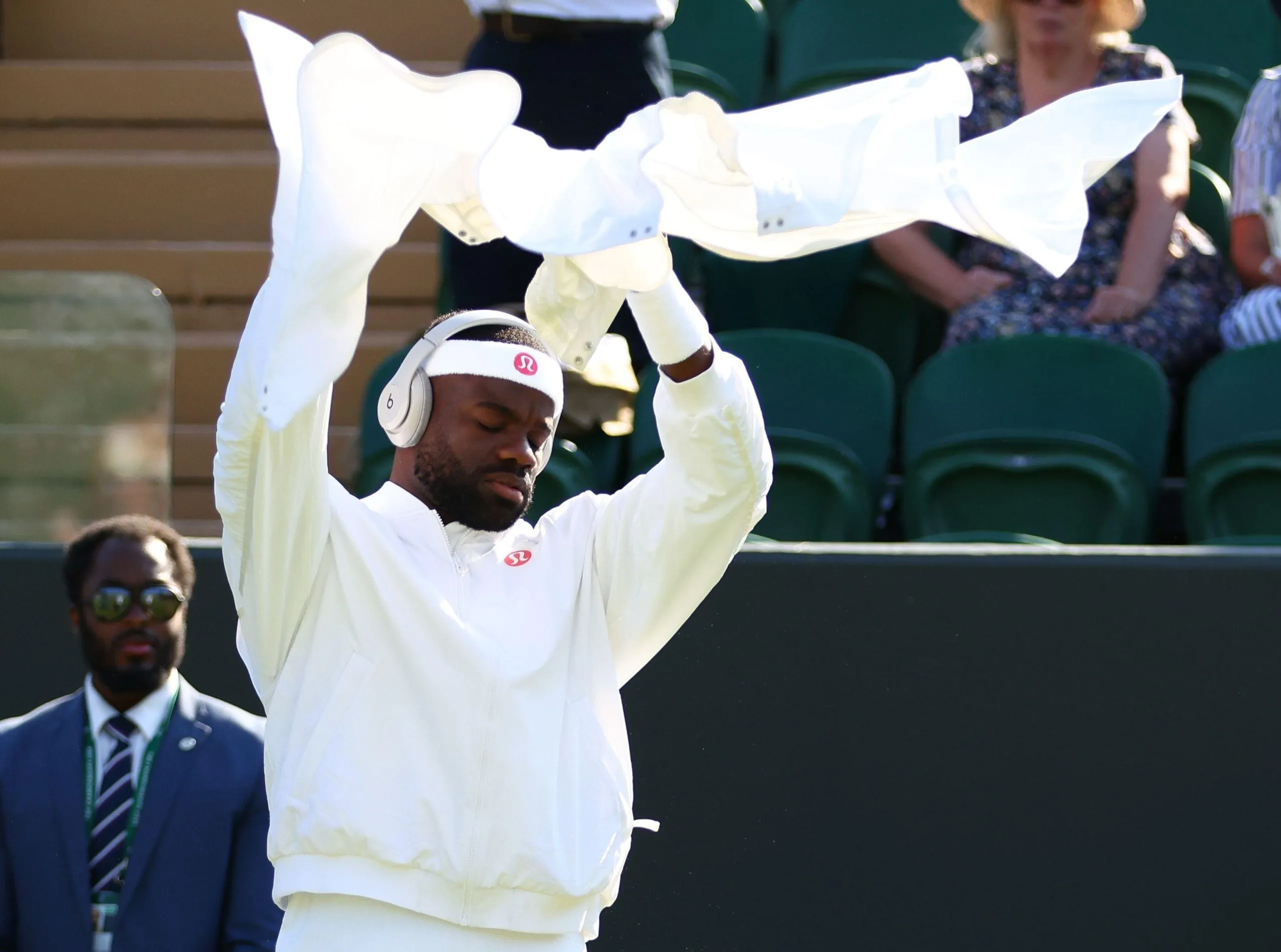 Tiafoe in headphones, arms aloft, holding white trousers