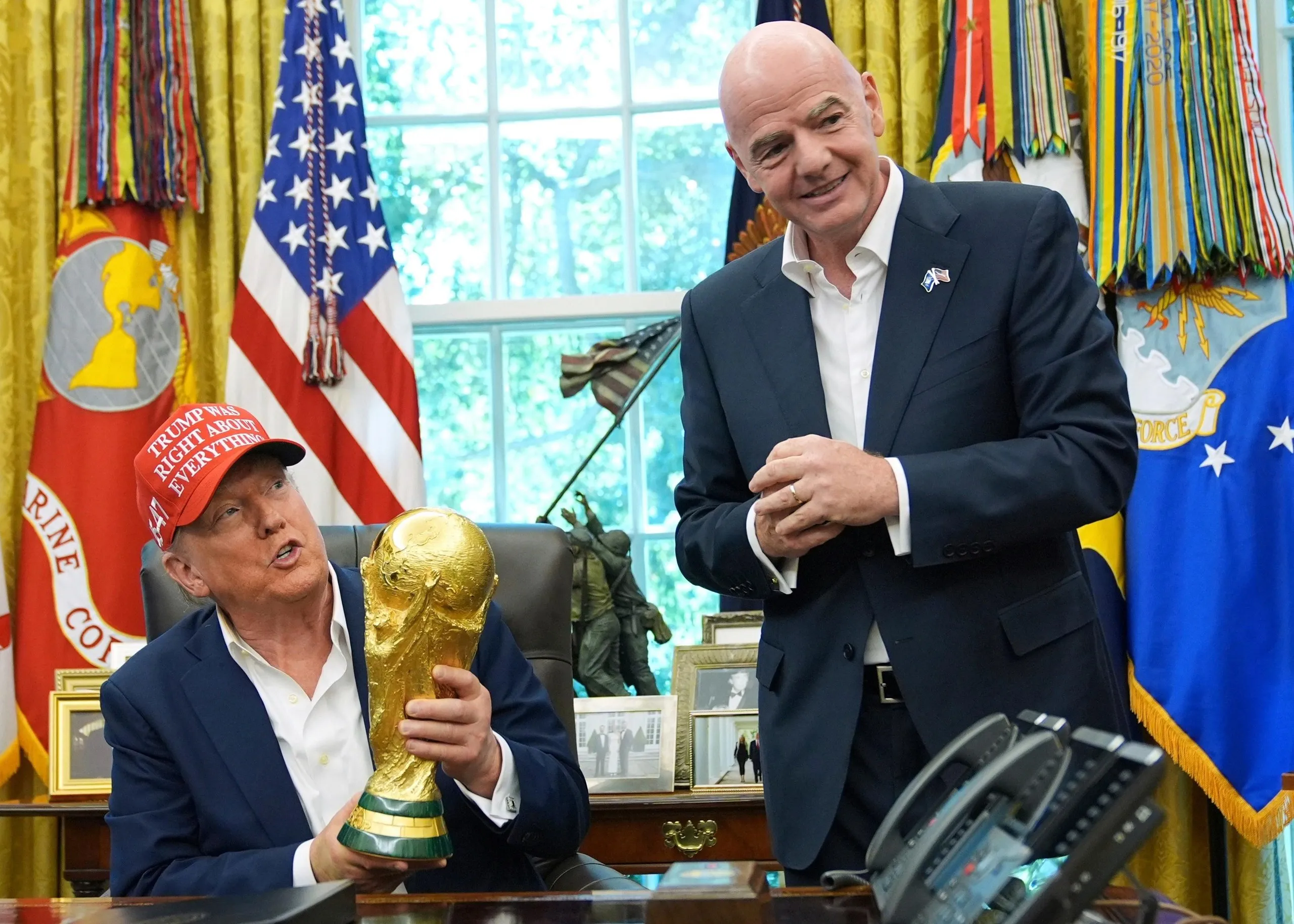President Donald Trump holds the FIFA World Cup trophy as FIFA President Gianni Infantino looks on