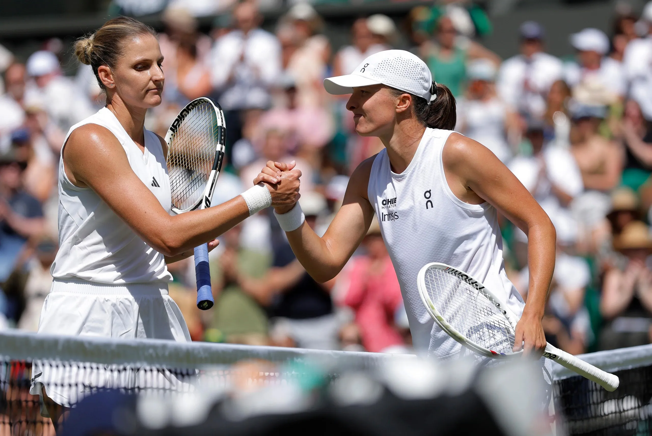 Iga Swiatek (right) shakes hands with Karolina Pliskova on Centre Court after her 6-1, 6-3 victory.