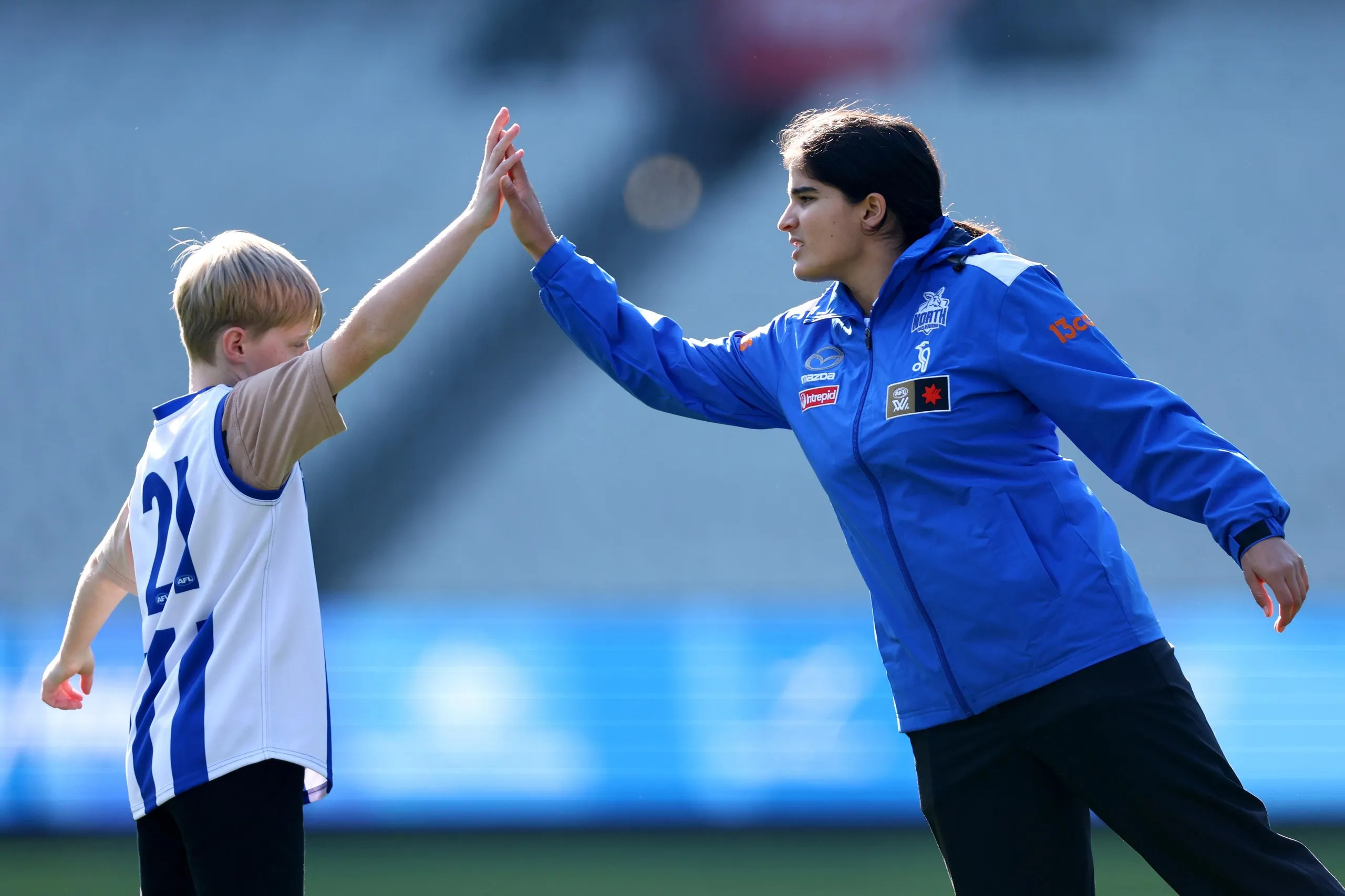 Zoe Savarirayan of the Kangaroos high fives a student from the AFL’s School Connect program
