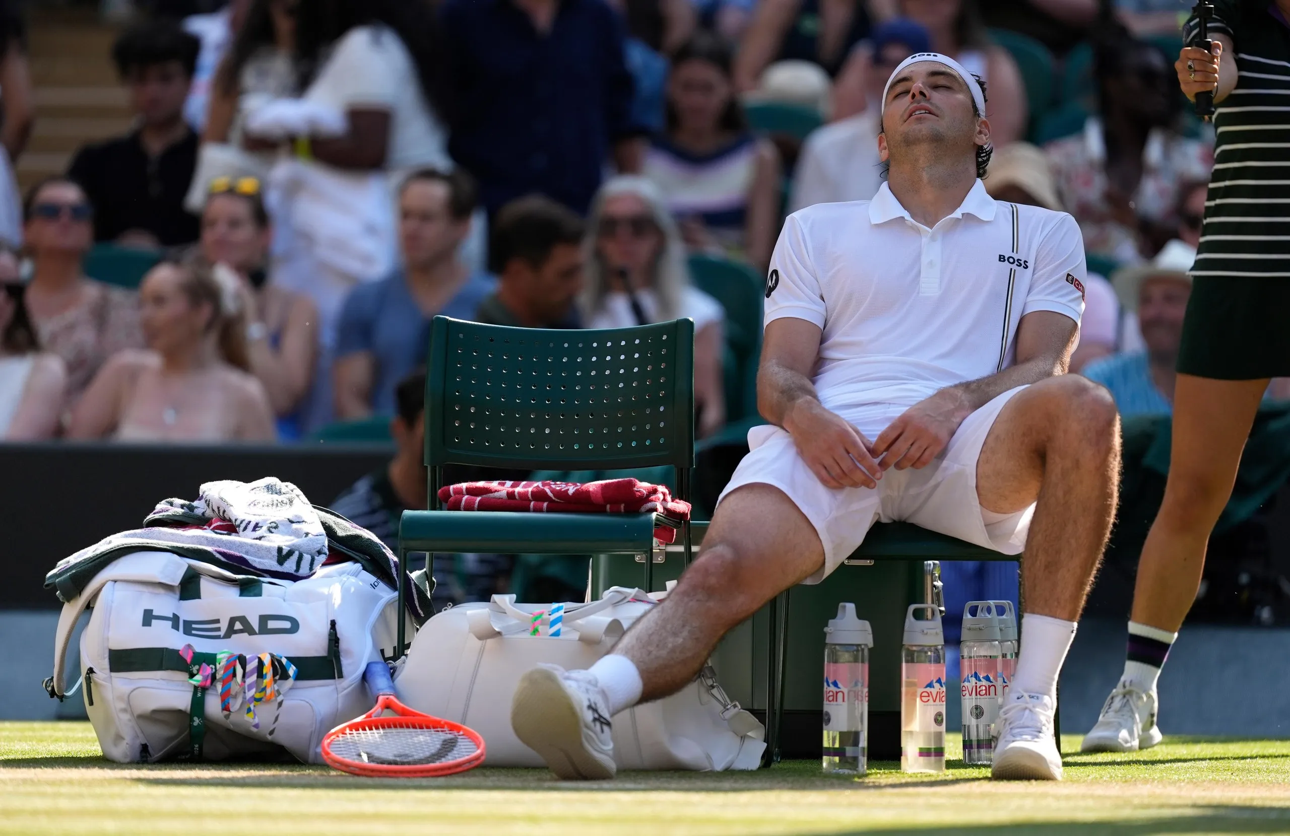 Taylor Fritz stretches out his injured knee during a change of ends