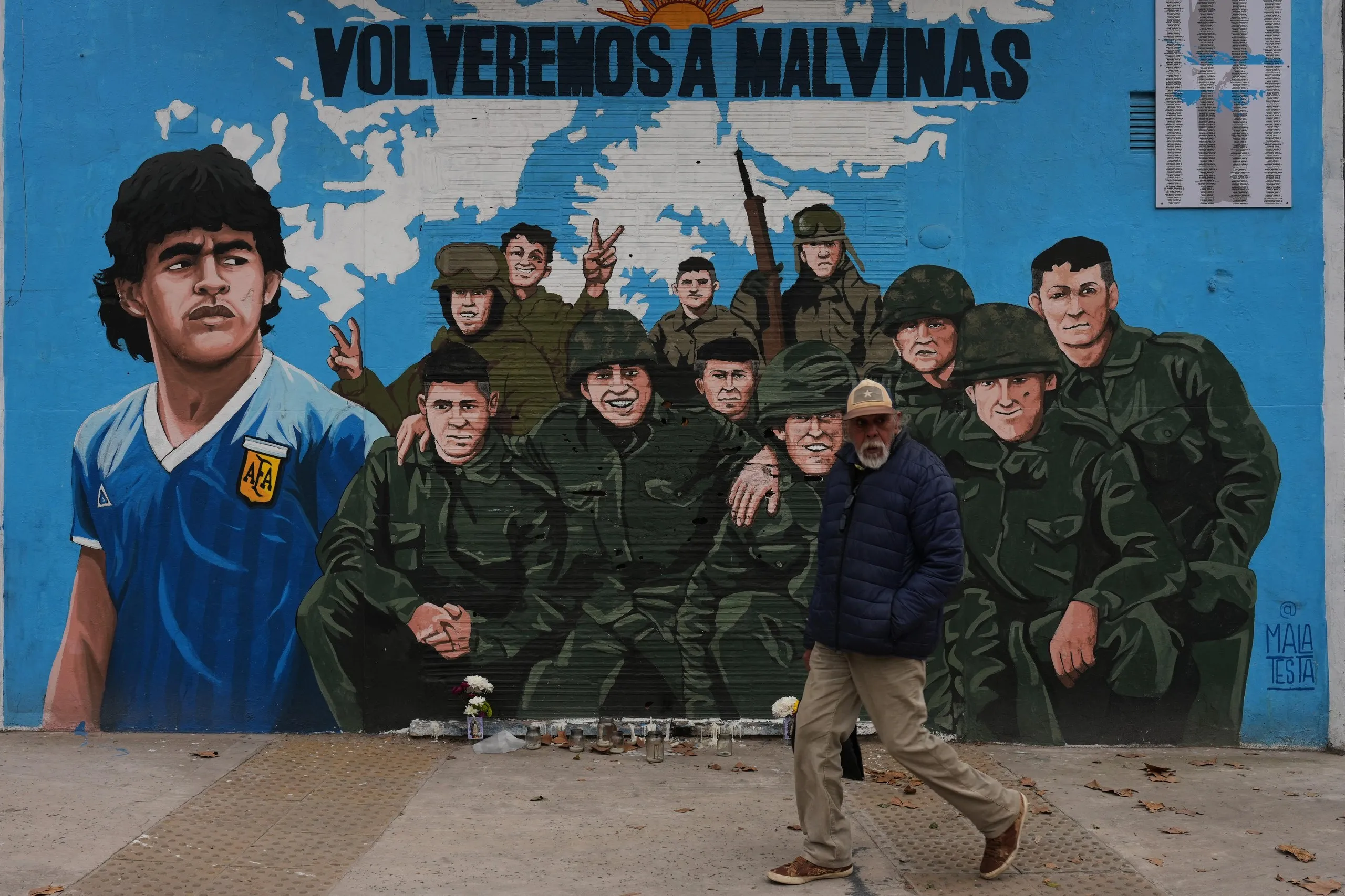 A man walks past a street mural in Buenos Aires depicting Diego Maradona and veterans of the 1982 war between Argentina and the United Kingdom over the Falkland Islands, known in Argentina as the Malvinas